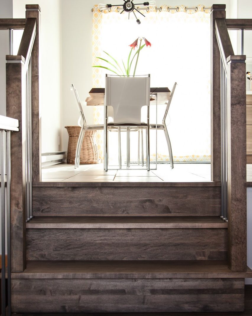 Un escalier d'érable teint gris, barreaux d'acier, ouvert sur une salle à manger