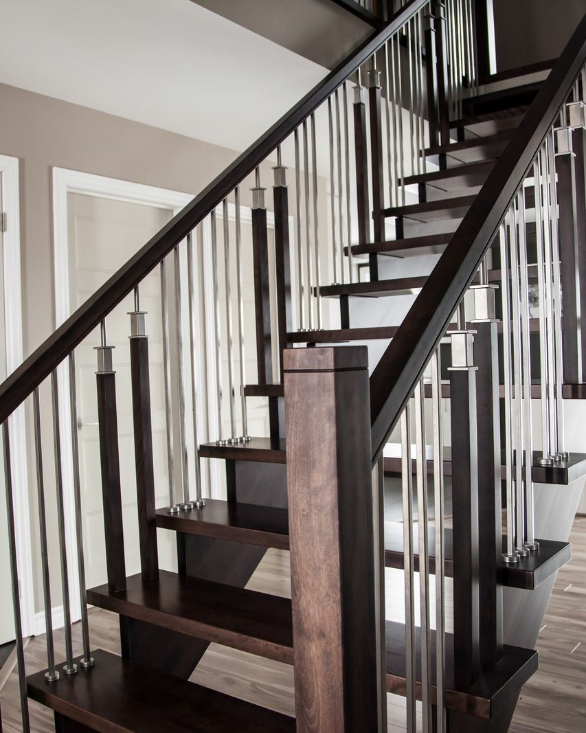 Un escalier de bois foncé aux barreaux d'acier, portes blanches au pied