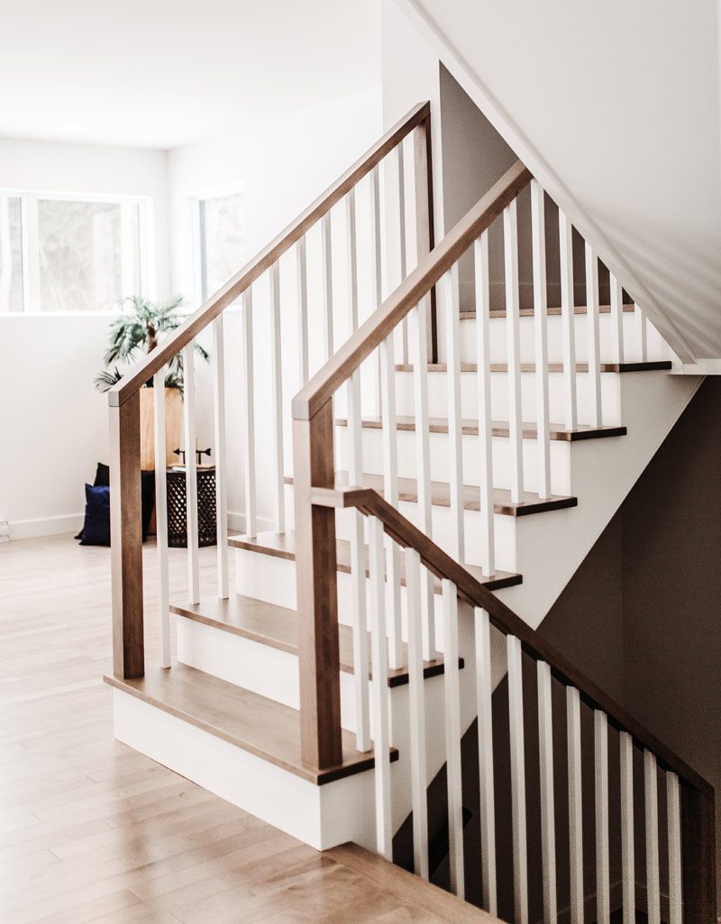 Un escalier de bois à barreaux blancs, main courante foncée, dans la salle de montre