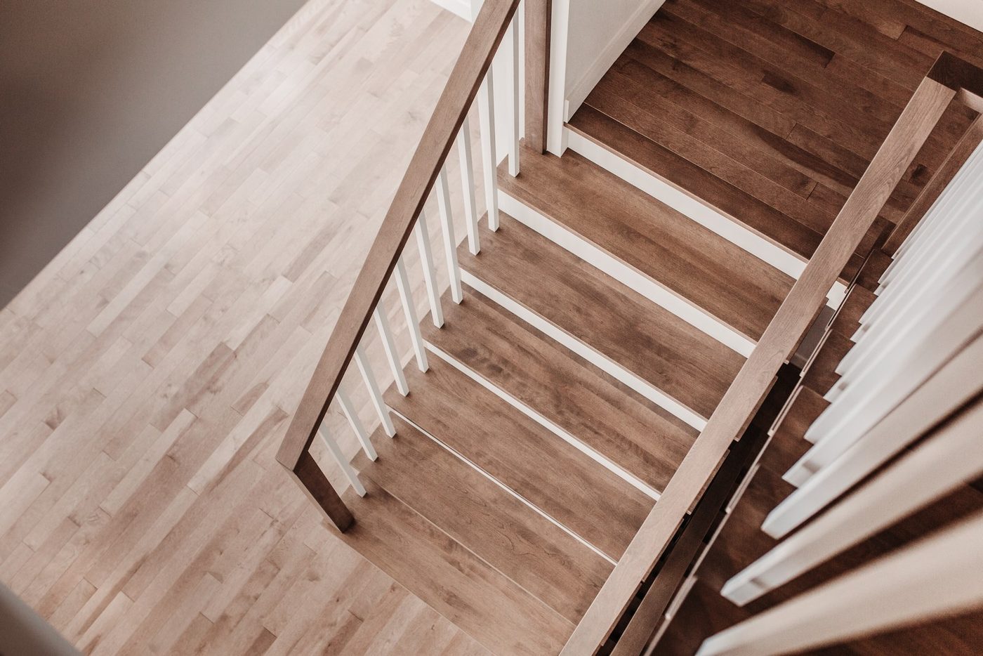 Vue plongeante sur un escalier tournant en érable, barreaux blancs, plancher de bois clair
